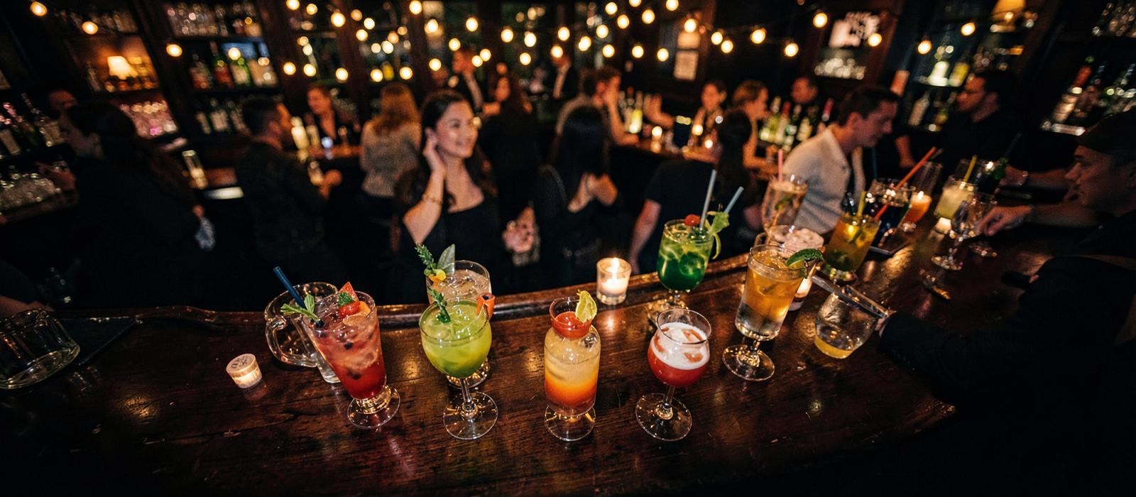 Barra de coctelería llena de copas y luces cálidas en hora punta